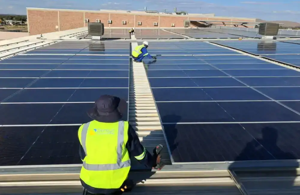 Technician working on a large commercial rooftop solar installation in Namibia under harsh sunlight conditions