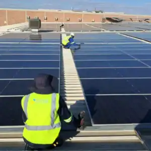 Technician working on a large commercial rooftop solar installation in Namibia under harsh sunlight conditions